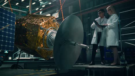 engineer and technician working on satellite construction. aerospace agency: diverse team of scientists using technological equipment and laptop computer to develop spacecraft for space exploration.