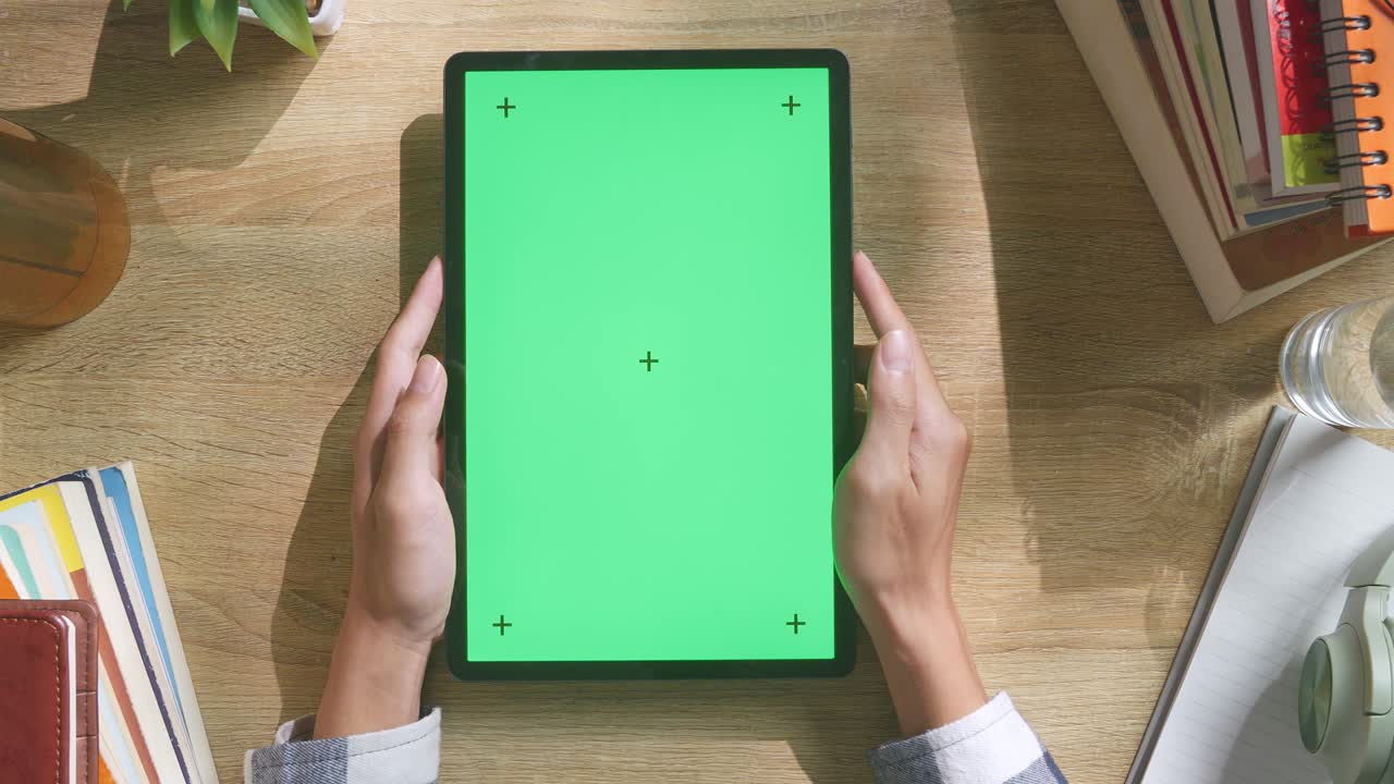 vista de arriba hacia abajo de una computadora portátil con pantalla verde simulada pantalla chromakey en un escritorio de oficina de madera al lado de la libreta con bolígrafos, gafas y un vaso de agua.