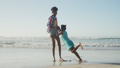 happy african american mother playing with daughter on sunny beach