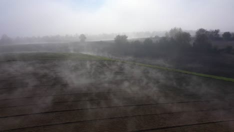 flying over rural field with thick fog in daytime