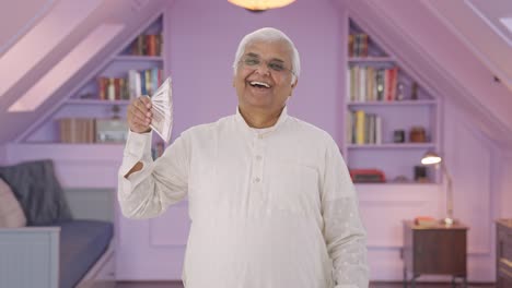 viejo indio feliz usando dinero como ventilador