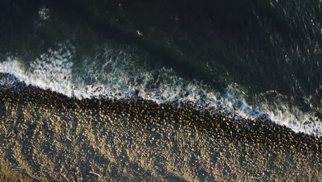 Slow-zoom-out-over-rocky-beach-on-Oregon-Coast,-breaking-waves-of-Pacific-Ocean