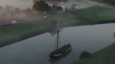 aerial view of traditional wooden sailing boat in canal during a misty morning, ijsselmeer, netherlands