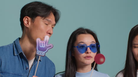 파란색 스튜디오 배경 앞에 있는 젊은 친구 그룹이 프로페션 1과 함께 사진 부스 스타일의 초상화에 포즈를 취하고 있습니다.