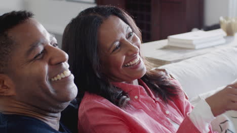 happy middle aged african american couple sitting together on the sofa watching tv, close up, elevated view