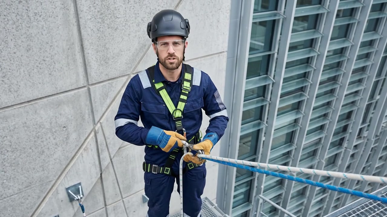 Industriekletterer bereitet Ausrüstung an der Gebäudeaußenfassade vor