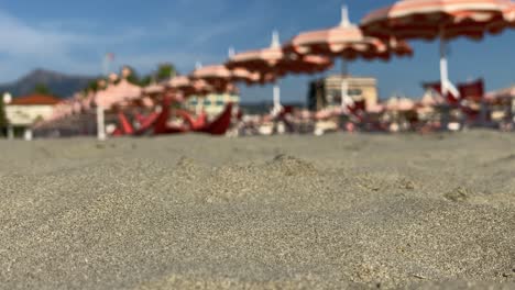 Playa-De-Arena-Sobre-Un-Fondo-Borroso-De-Sombrillas-De-Playa-En-La-Brisa-Fresca