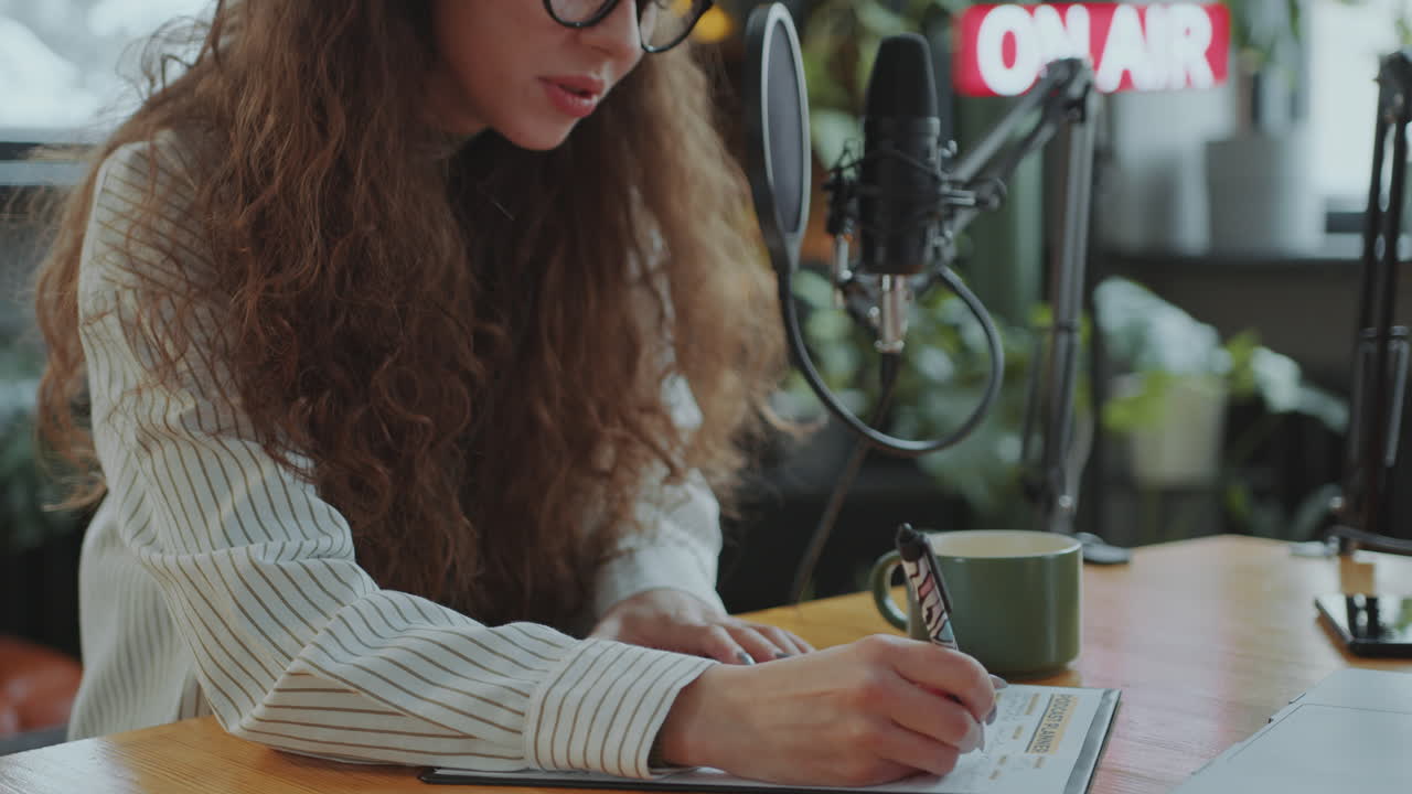 podcaster femenina escribiendo un plan de contenido en un escritorio en un estudio de grabación