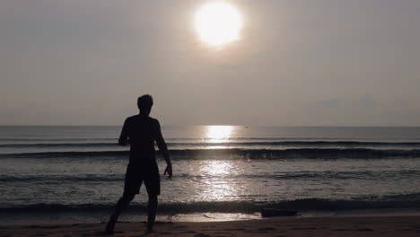 man walking towards ocean by sunrise in asia to take morning swim in slow motion