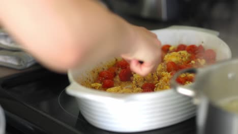 mujer revolviendo salsa de pasta e ingredientes con una cuchara de madera en un tazón blanco