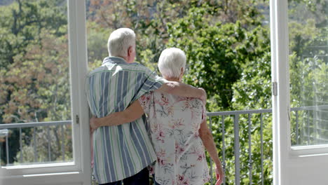 Happy-senior-caucasian-couple-standing-on-balcony-and-embracing,-slow-motion