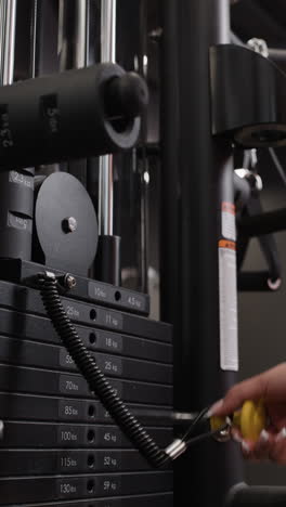 woman adjusting weights on a gym machine