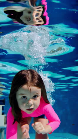 young girl swimming and playing underwater in a pool