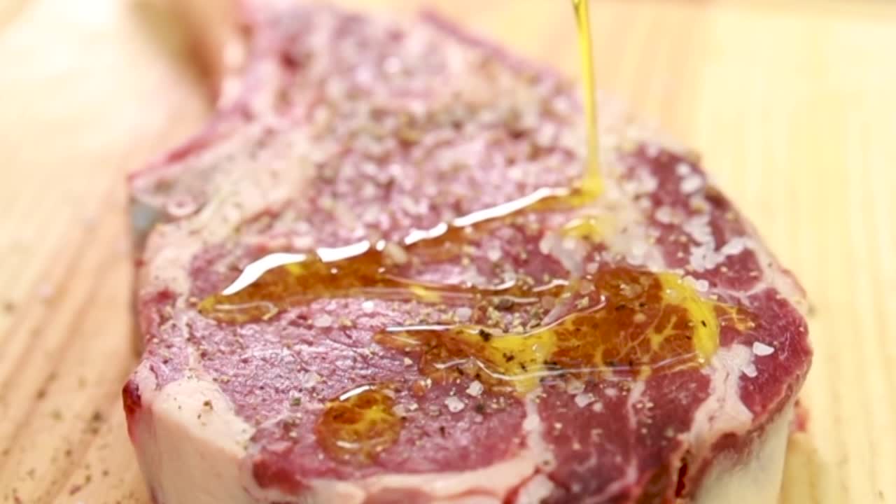 Preparazione di una bistecca con olio d'oliva e condimenti