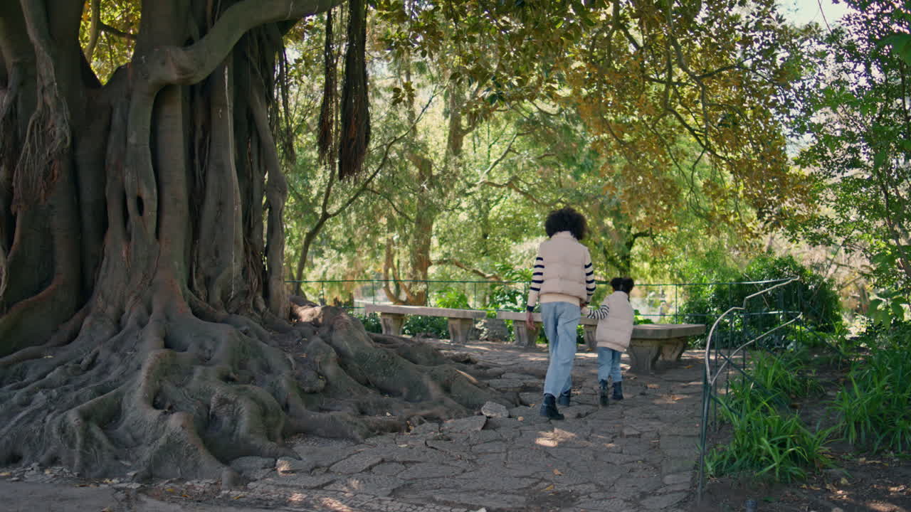 파크 트리 근처에서 산책하는 행복한 엄마의 아이 빛 날. 가족이 주말을 즐긴다.