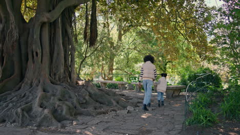 happy mom child walking near park tree sunny day. family enjoy weekend.