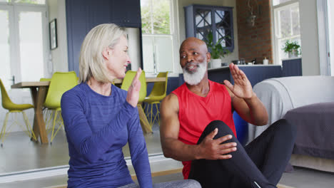 Mixed-race-senior-couple-high-fiving-each-other-at-home