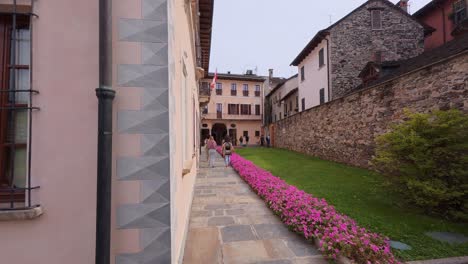 charming alleyway in orta san giulio, italy, with lush greenery and colorful flowers leading to a historic building