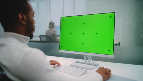 businessperson working on computer with green screen