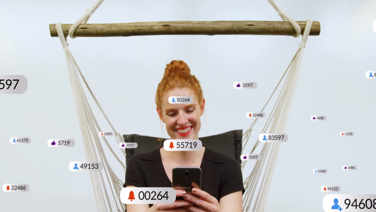 Using smartphone with social media notifications, woman relaxing in hammock smiling