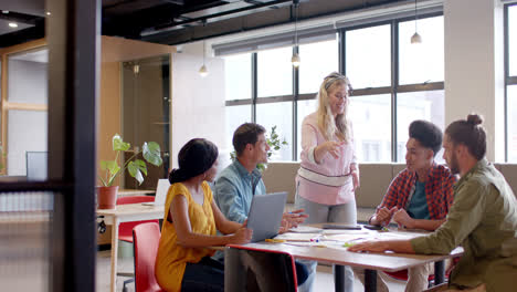 Happy-diverse-colleagues-brainstorming-with-documents-and-laptop-at-table-in-office-in-slow-motion