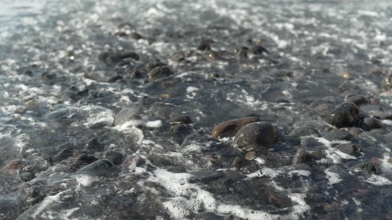 Foamy waves flow over stone beach in Tenerife