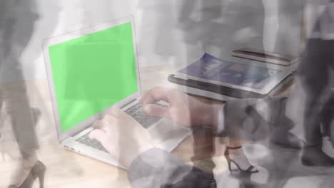 Animation-of-hands-using-laptop-with-green-screen-over-sped-up-commuters-walking-in-modern-building