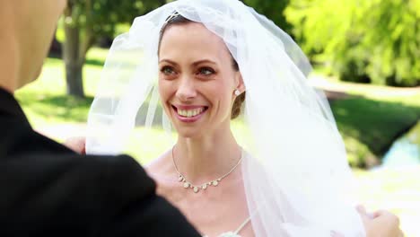 Groom-lifting-veil-off-beaming-brides-face