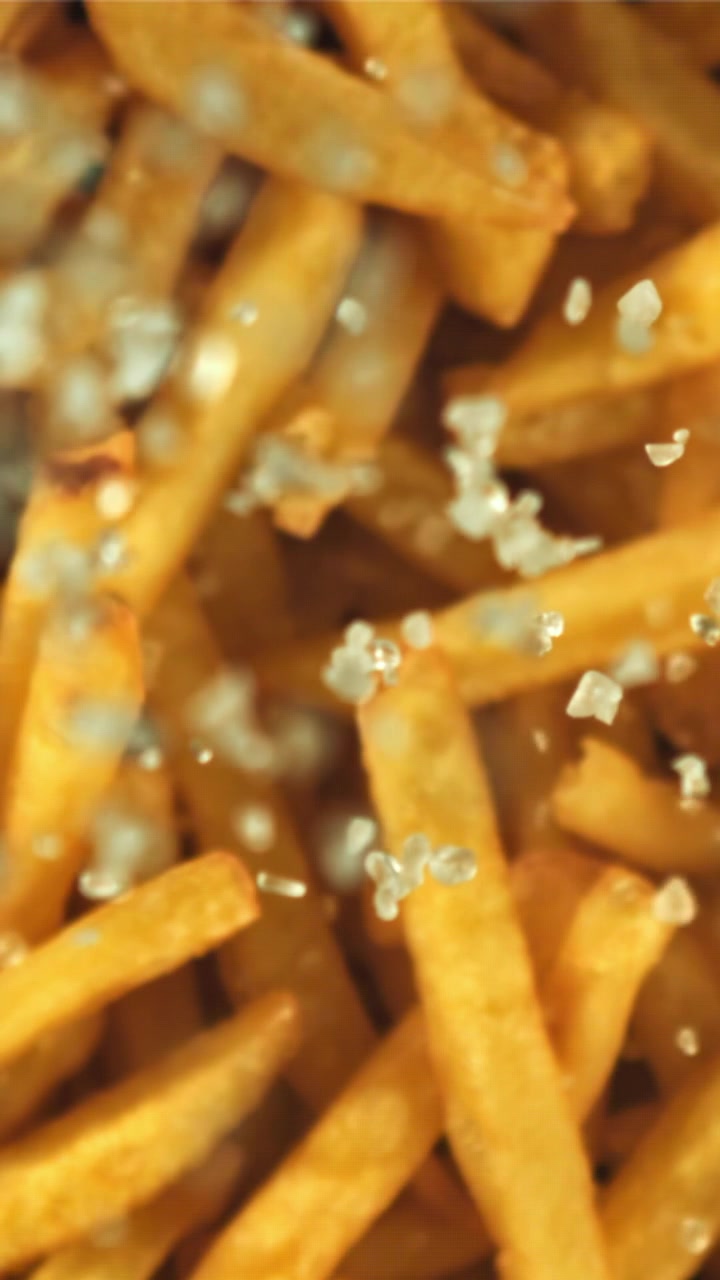Salt Crystals Falling onto Crispy Golden French Fries