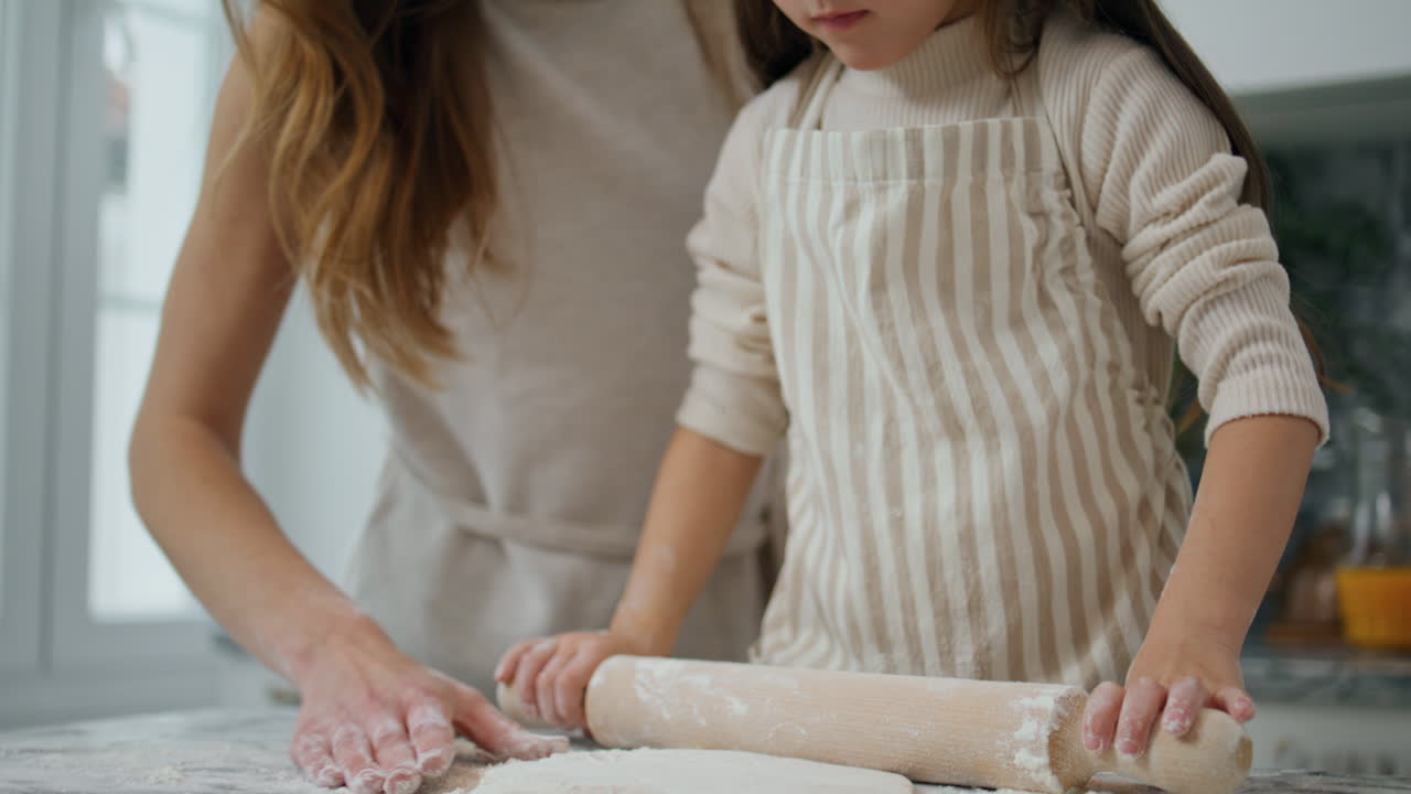 madre hija rodando la masa a casa de cerca. mujer sonriente enseñando a los niños a cocinar