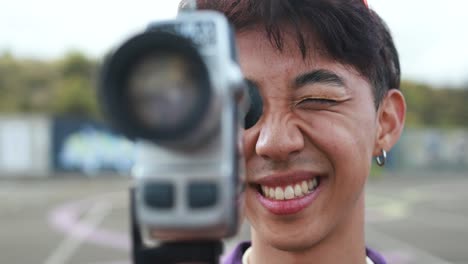 young asian man using vintage old video camera outdoor