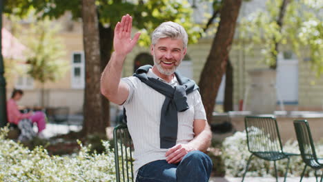 Mature-man-tourist-smiling-at-camera-waving-hands-gesturing-invitation-hello-hi-greeting-goodbye