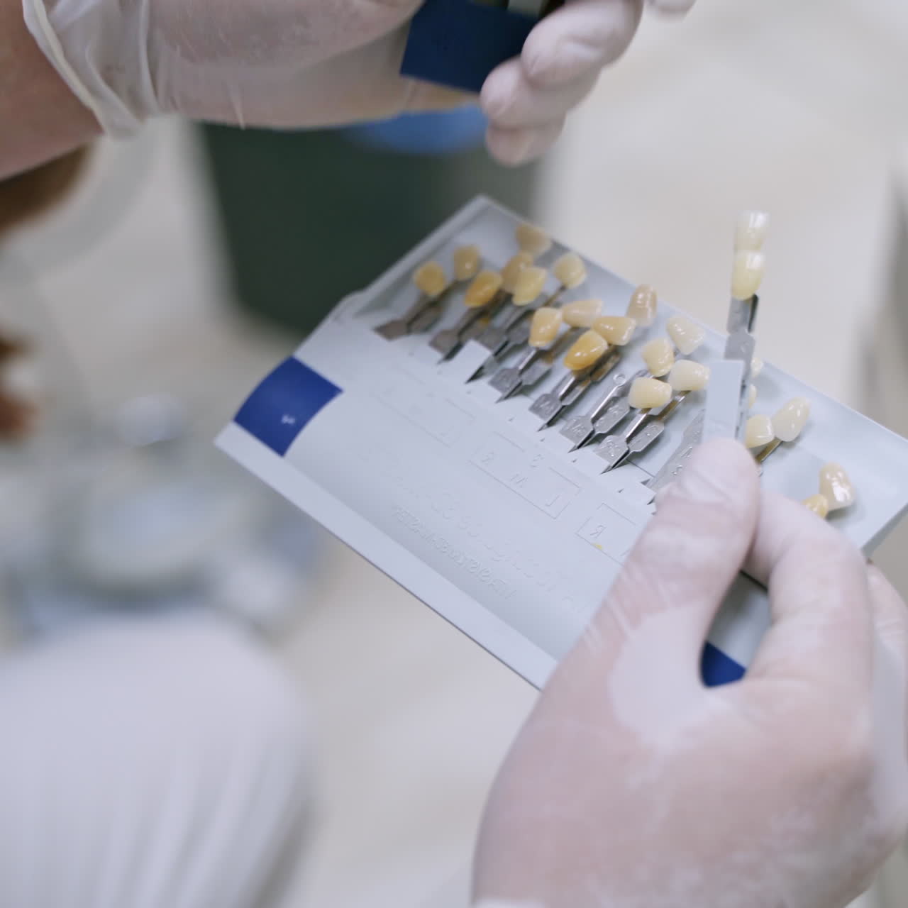 Dentist holding artificial teeth. Stomatologist in white sterile gloves choosing color of synthetic tooth. Benefits of tooth implants.