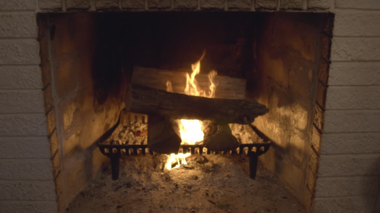 A roaring fire in a vintage brick fireplace in a cozy living room. Classic burning logs. Shot in 60 frames for slow motion