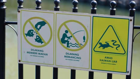 warning signs at a park or pond: no feeding, no fishing, beware of wild animals