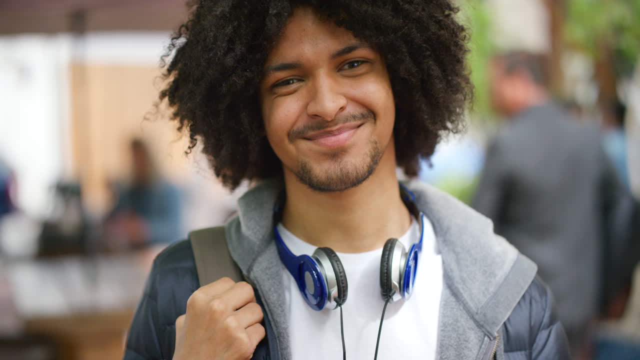 Homme afro branché souriant à l'extérieur en milieu urbain