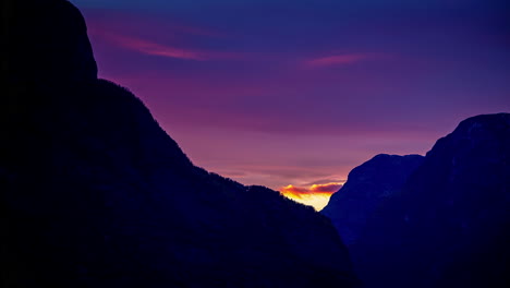 time lapse shot of purple sunset with flying clouds behind mountains in norway