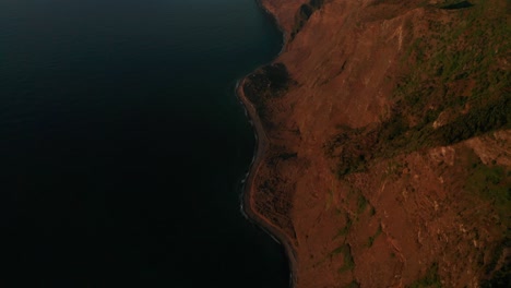 Sunset-glow-illuminates-wild-rocky-shore-of-Madeira,-aerial