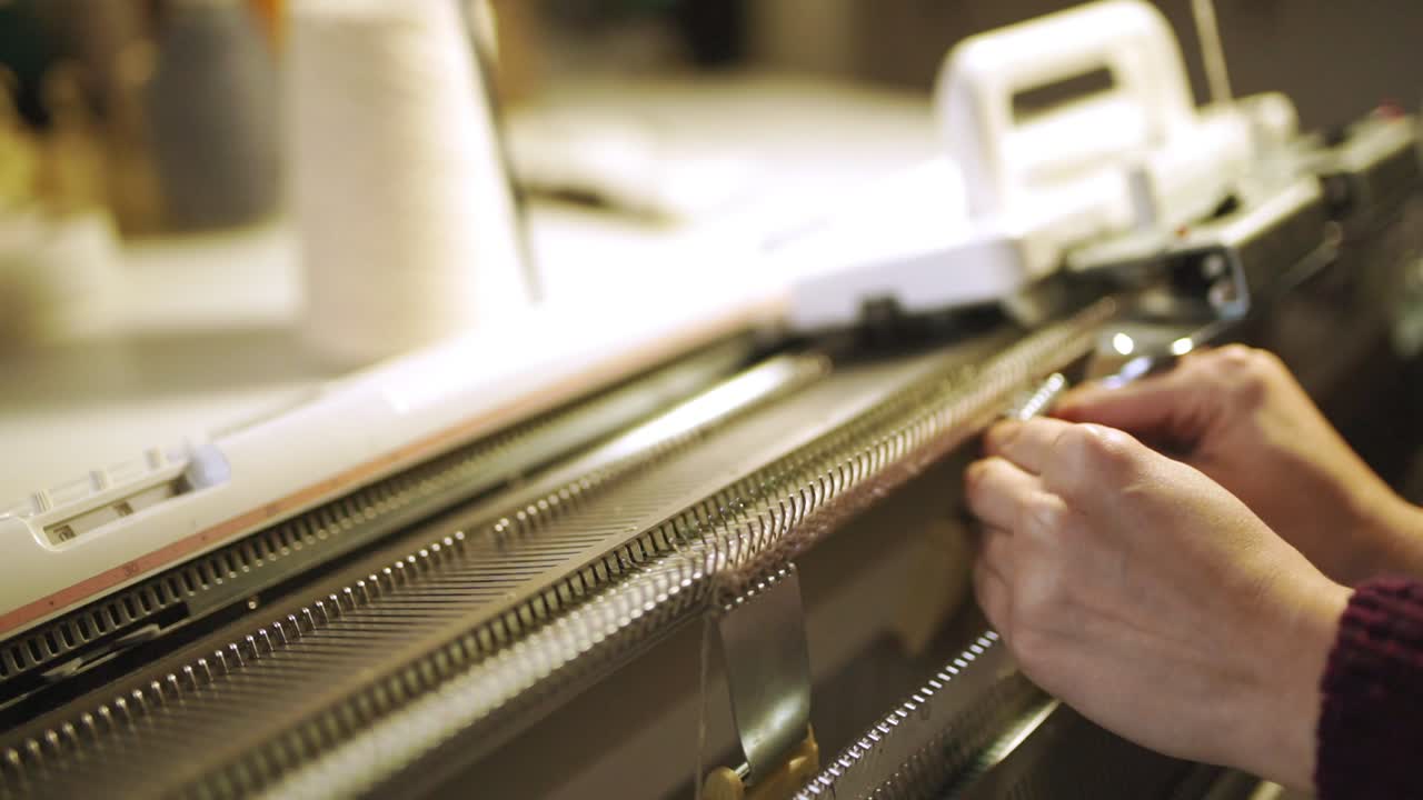 Female hands making knitted fabric on weaving machine in workshop
