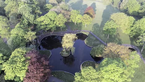 deserted peaceful public park aerial view of lush lake garden above treetop orbit right