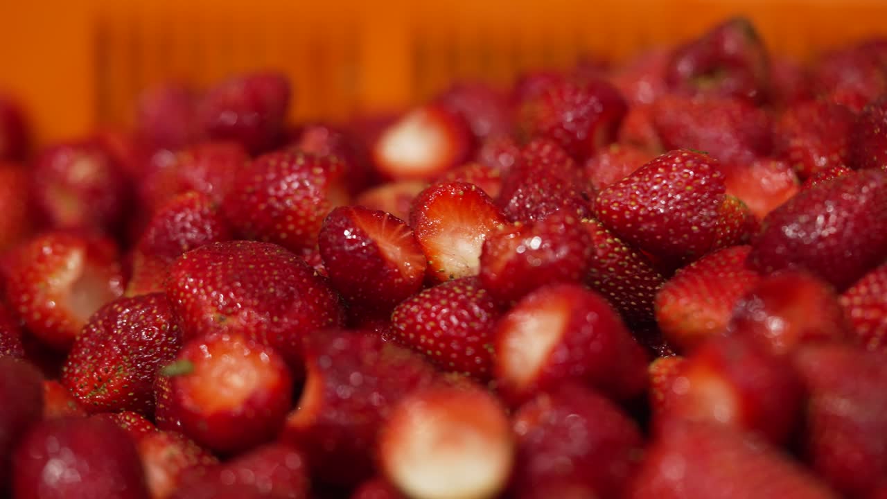 una gran cantidad de fresas con unas pocas más siendo arrojadas a la pila siendo procesadas en una fábrica