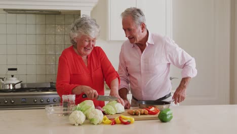 Kaukasisches-älteres-Paar,-Das-Zu-Hause-In-Der-Küche-Gemeinsam-Gemüse-Hackt