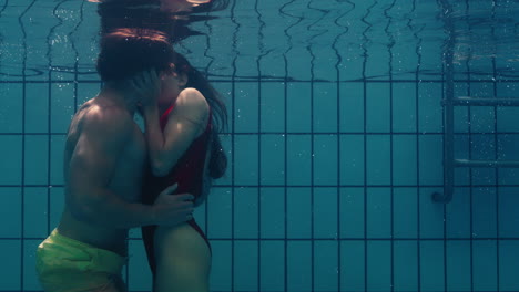 Romantisches-Paar,-Das-Sich-Unter-Wasser-Im-Schwimmbad-Küsst.-Verliebte-Junge-Menschen-Genießen-Innige-Küsse.-Liebende-Tauchen-Im-Wasser-Auf-Und-Schweben-Mit-Blasen-In-Leidenschaftlicher-Intimität