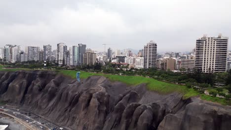 aerial orbital shot showing a paraglider doing wingovers over the highway while cars are driving below