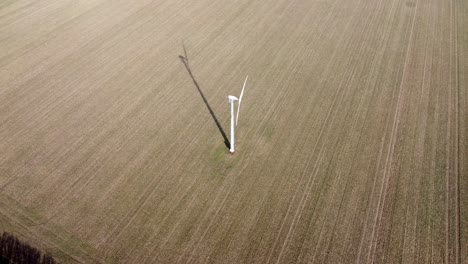 a windturbine spinning with long shadow in a field