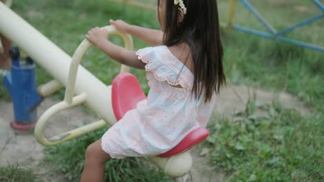 a pregnant mother and her young daughter enjoy playful time together at a playground in the park, surrounded by trees and greenery