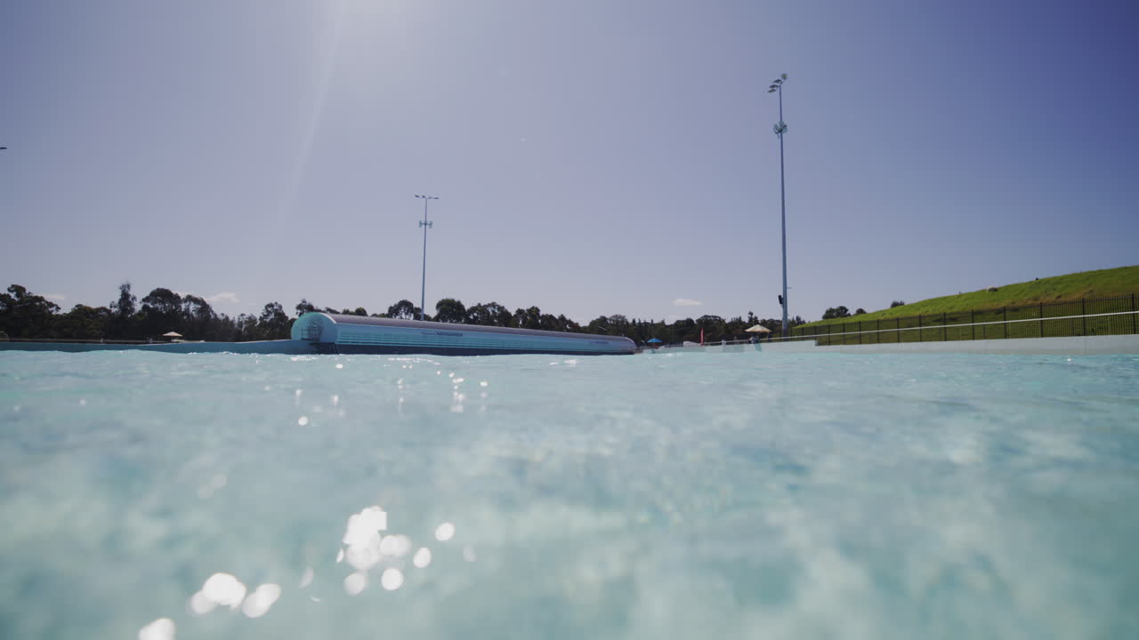 Slow motion underwater view with sunlight streaming across pool floor