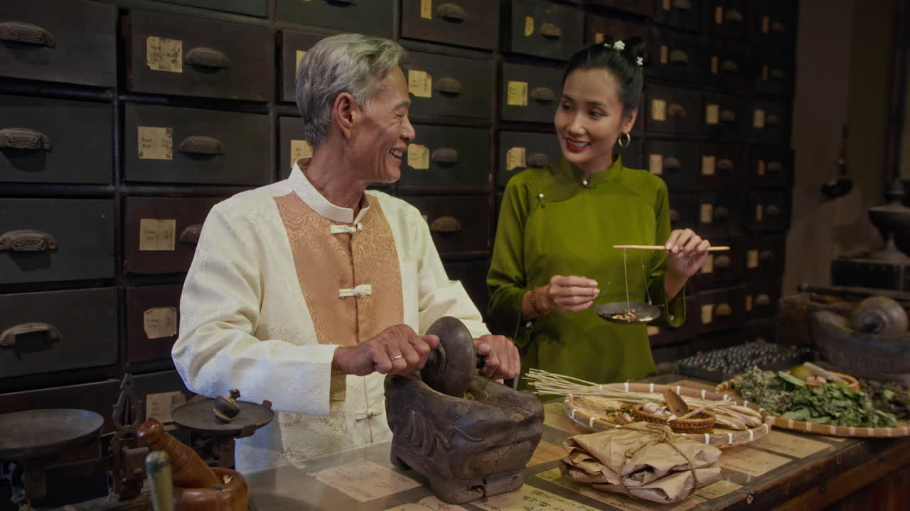 Aged Healer Grinding Ingredients and Talking to Colleague at Pharmacy