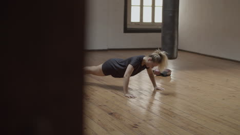 long shot of focused woman doing push-ups in practice room