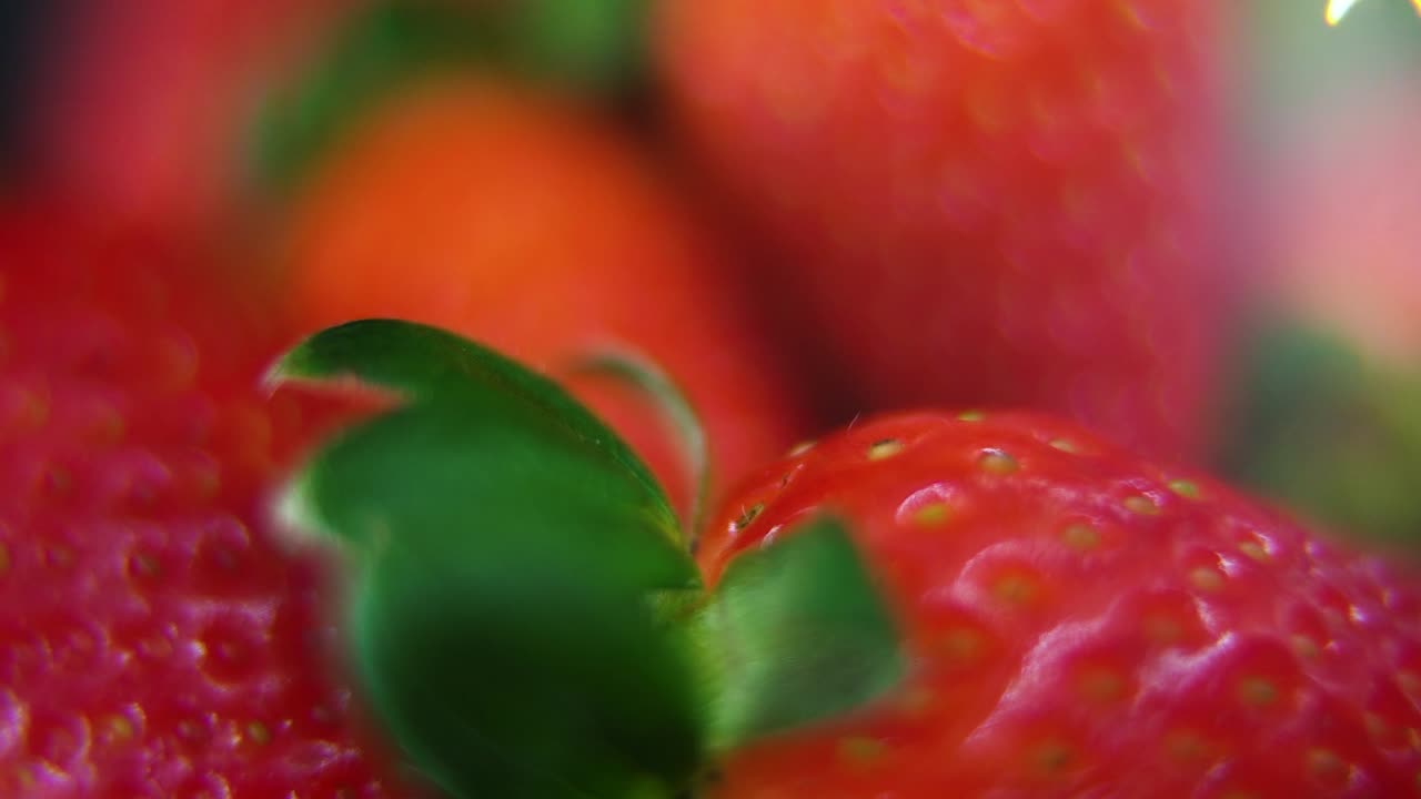 Macro detailed video of a pile of strawberries, red RAW strawberry, green leaf, tiny seeds, on a rotating stand, smooth movement, slow motion 120fps